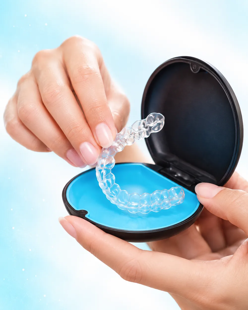A clear aligner being placed into its carry case